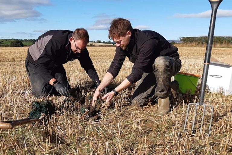 Joe Martlew in a farm field taking soil samples